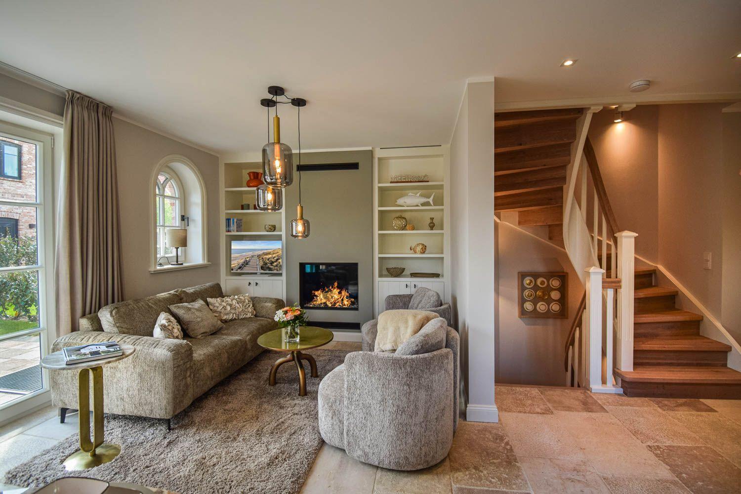 Wohnzimmer mit Kamin, Sitzgelegenheiten und Treppe zur oberen Etage.