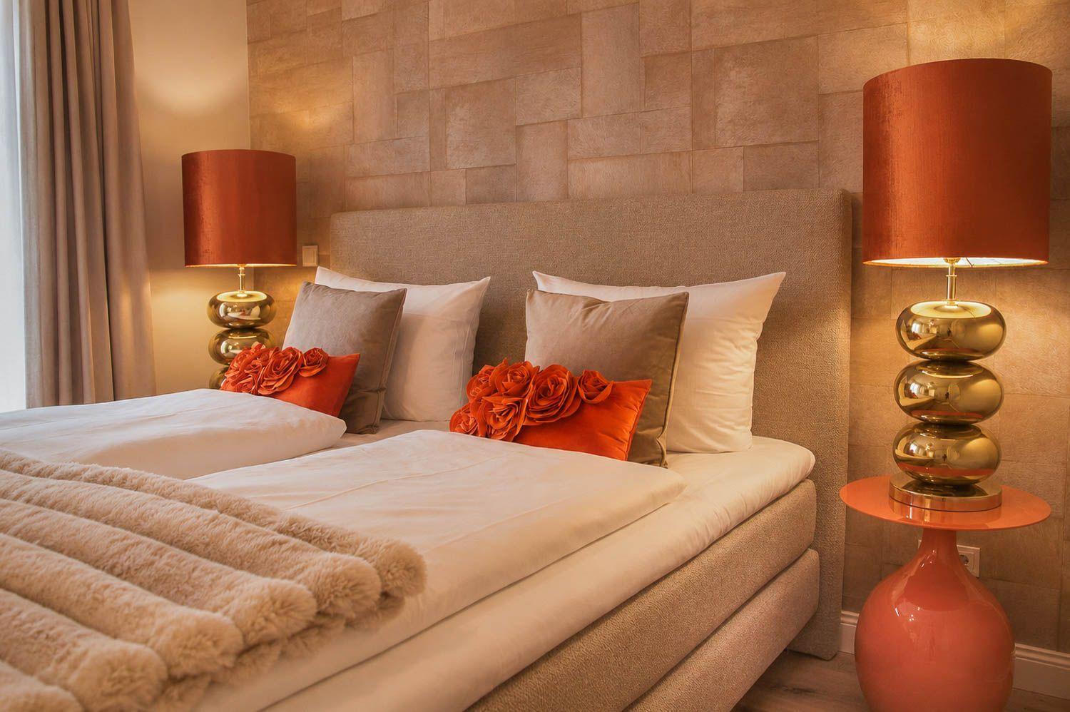 Ein Bett mit Kissen und Decke, zwei Nachttische mit Lampen und eine Wand mit Paneelen.