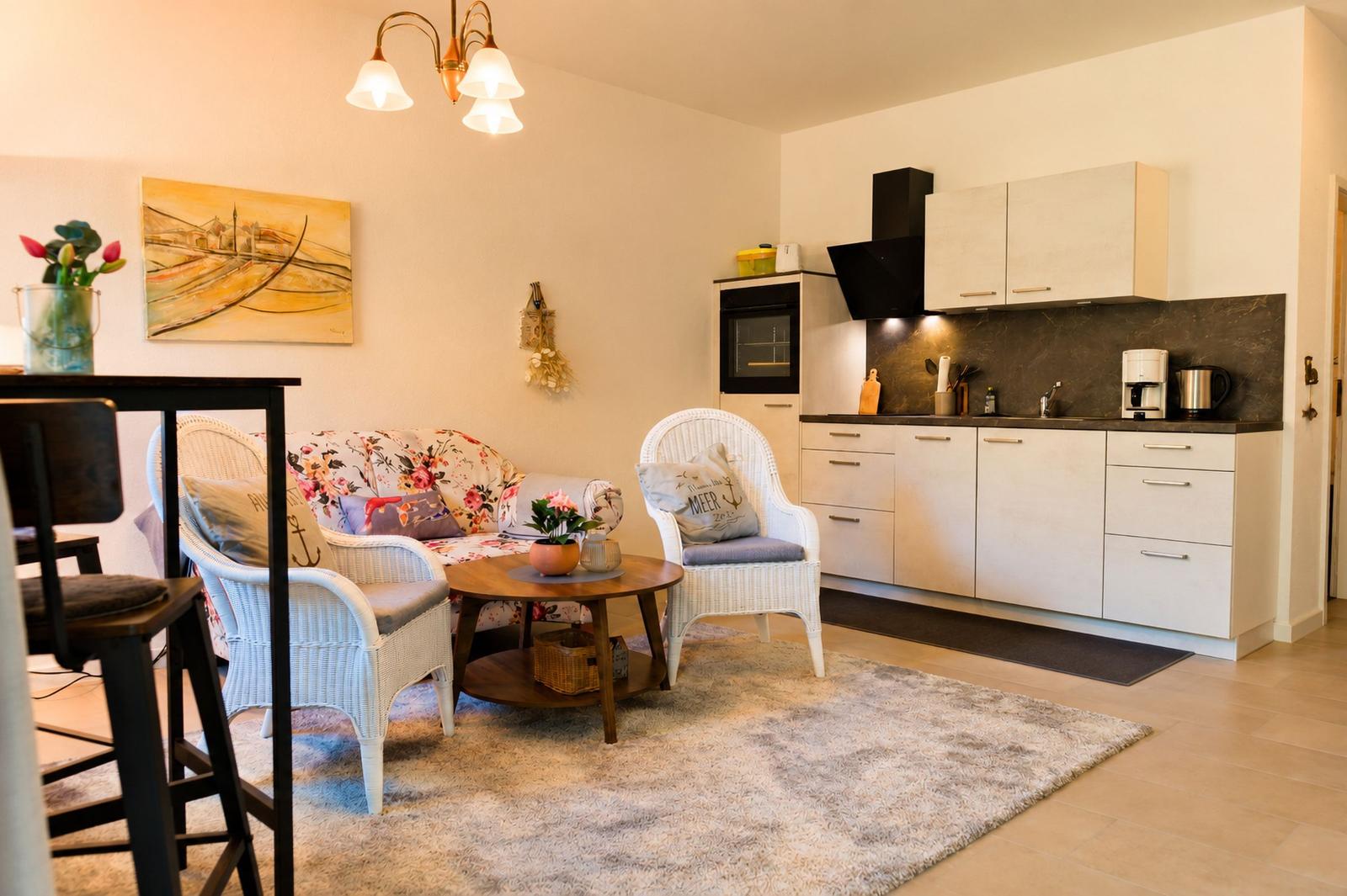 Wohnküche mit weißen Wickerstühlen, gemustertem Sofa und Küchenschränken.
