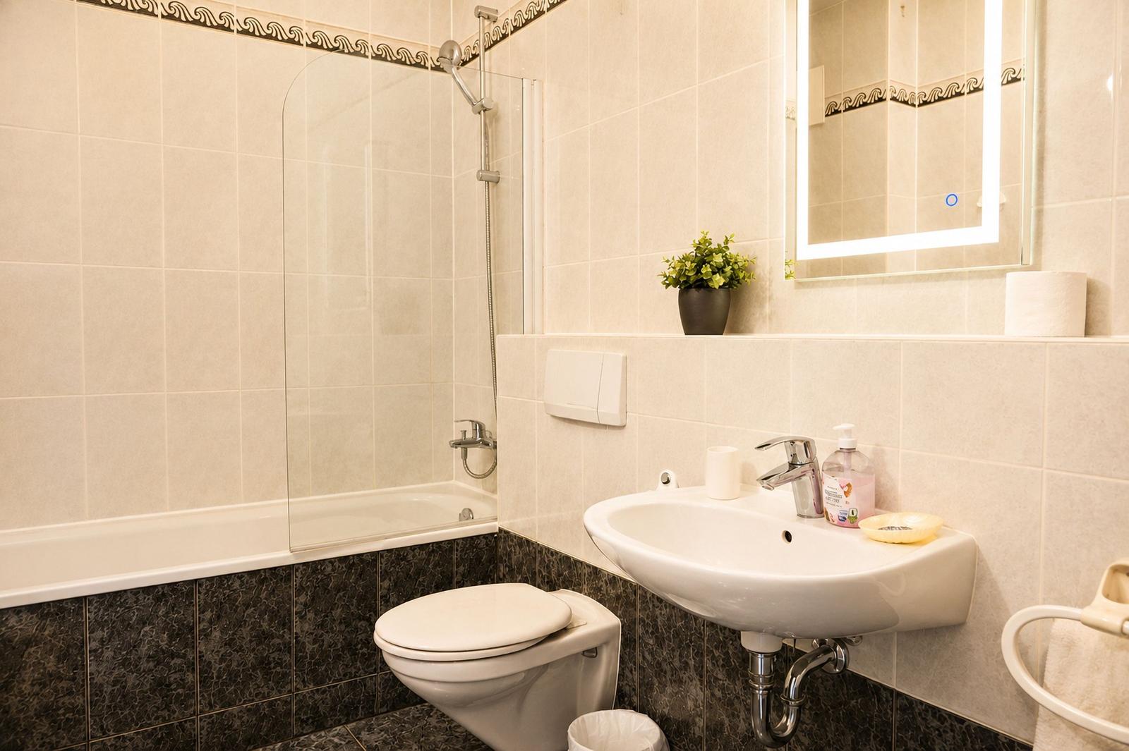 Badezimmer mit Badewanne, Duschkabine, Waschbecken und Spiegel.