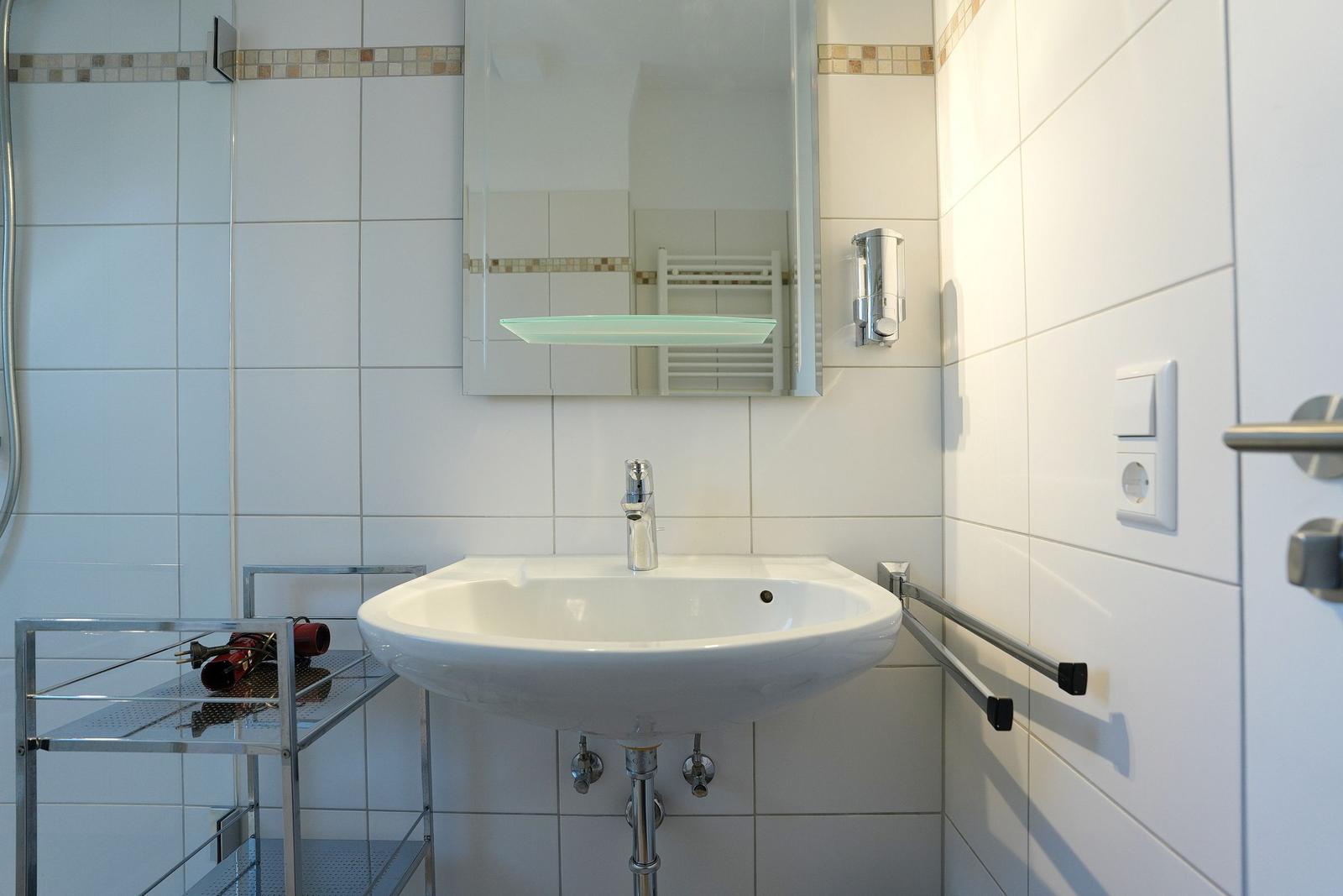 Badezimmer mit Waschbecken, Spiegel und Dusche.