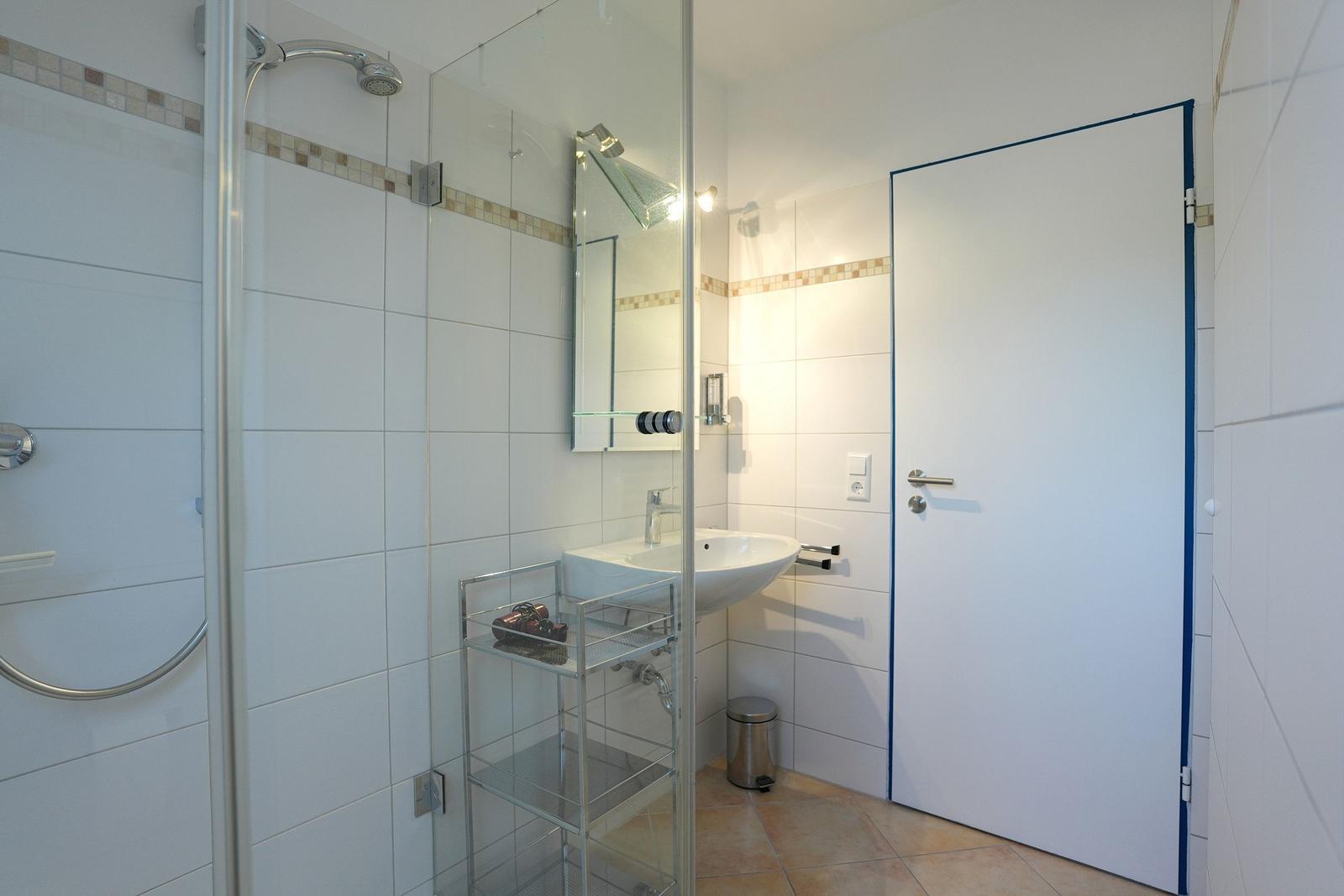 Badezimmer mit Dusche, Waschbecken und Spiegel