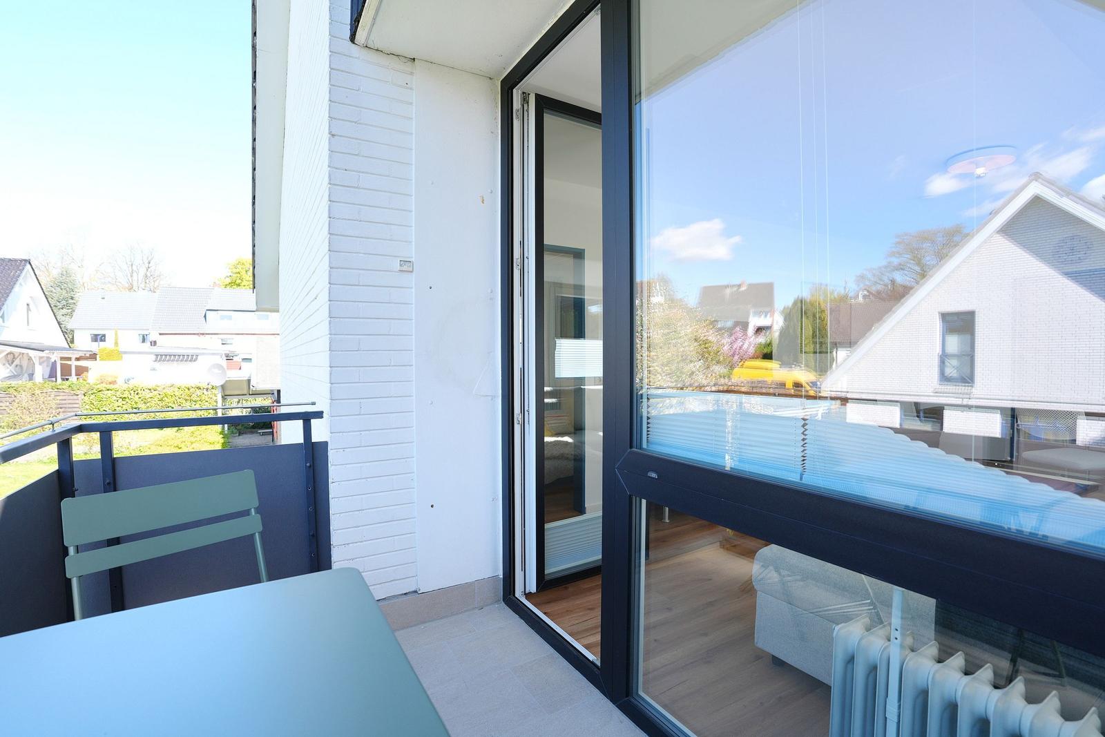 Terrasse mit Tisch und Stuhl, Blick ins Haus mit Sitzgelegenheit.