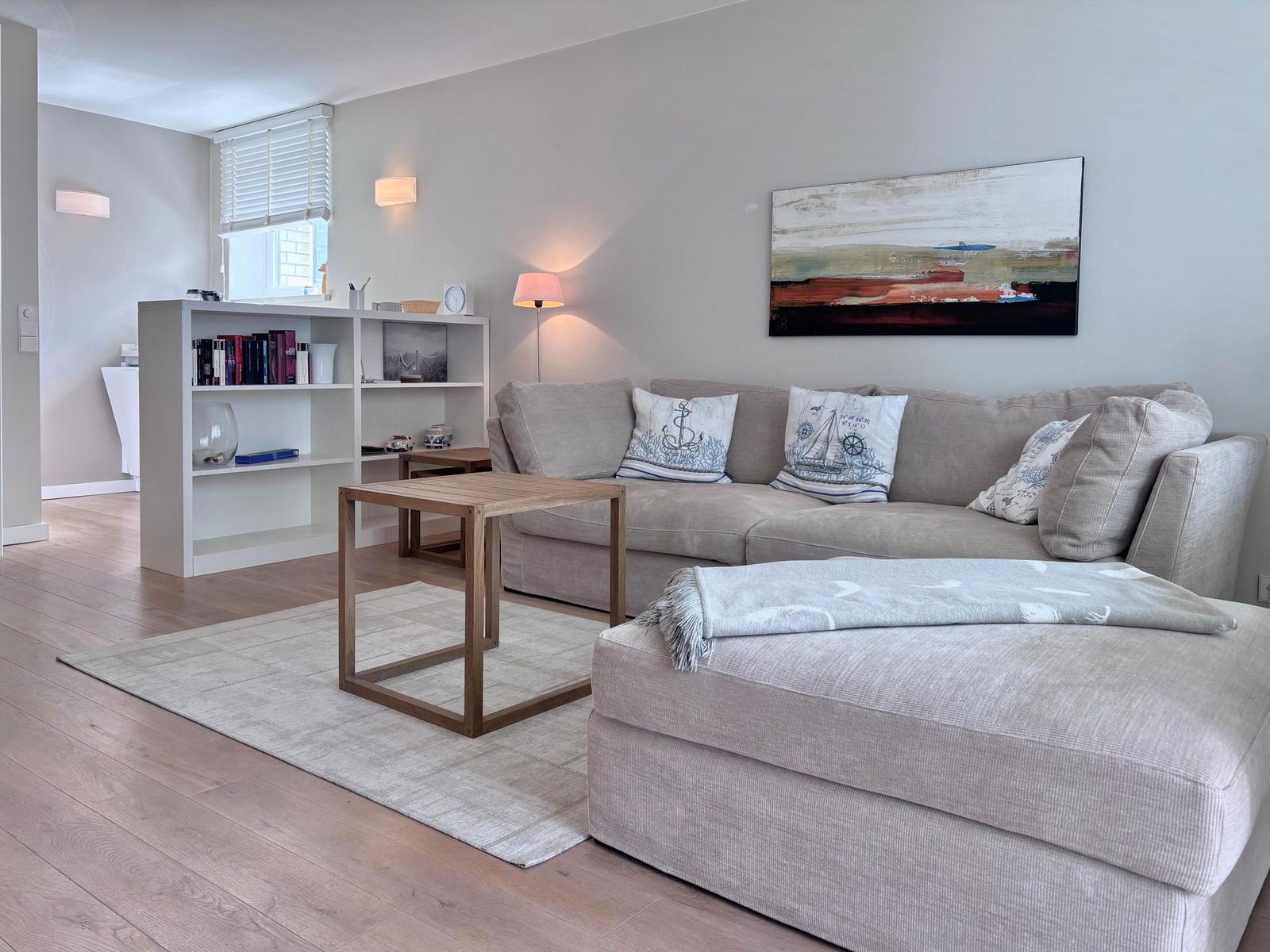 Ein Wohnzimmer mit grauem Sofa, Holztisch und Wandbild.
