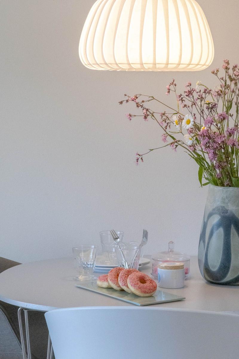 Runder Tisch mit Donuts, Blumen und Lampe. Moderne Einrichtung.