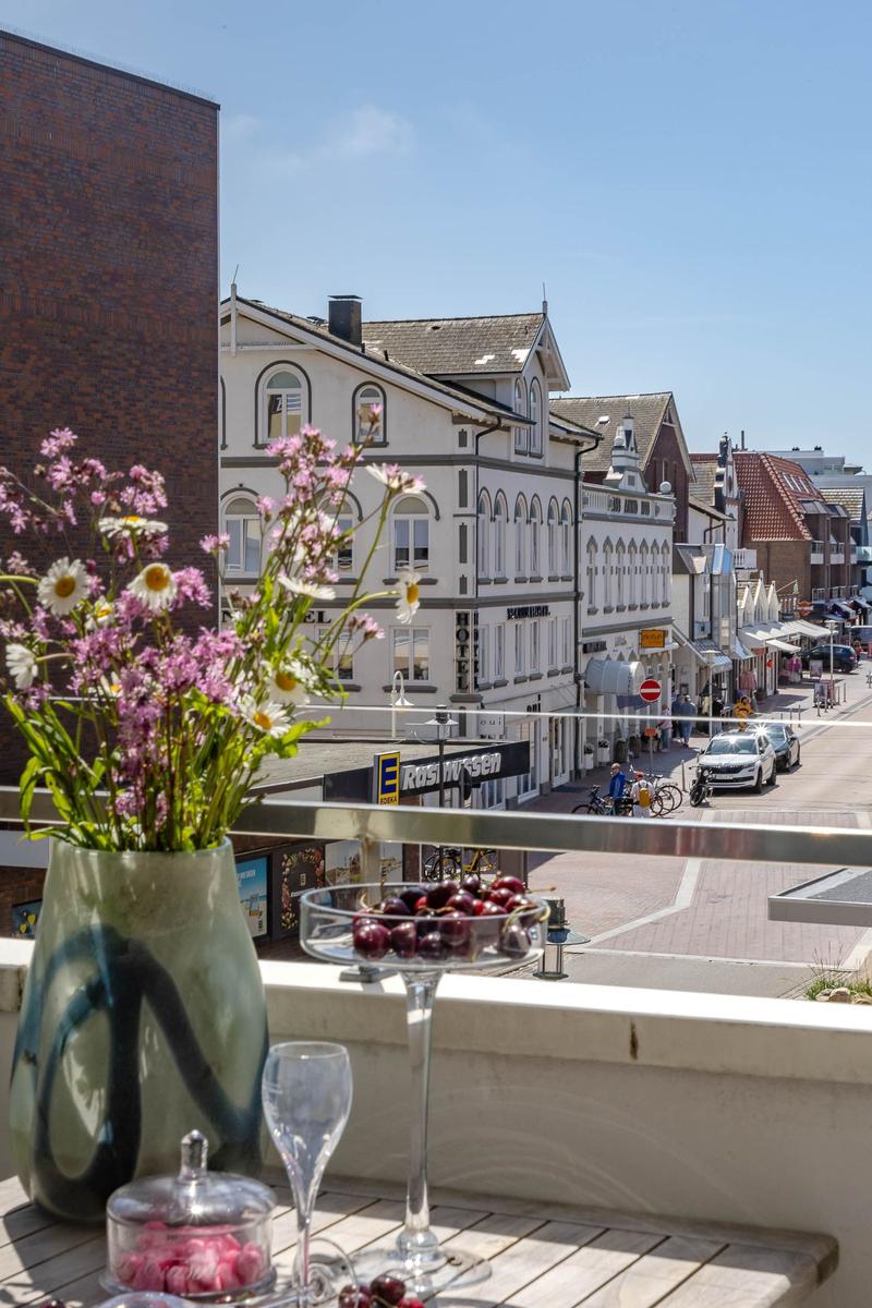 Balkon mit Blumen und Obst, Blick auf Straße und Gebäude.
