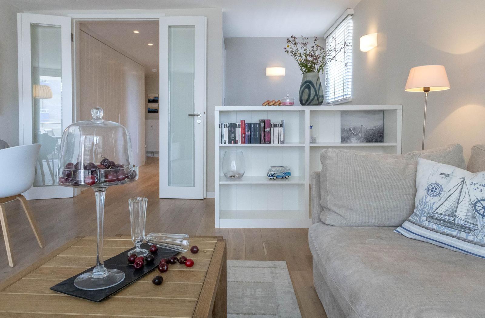 Wohnzimmer mit Sofa, Bücherregal und Tisch mit Kirschen unter Glas.