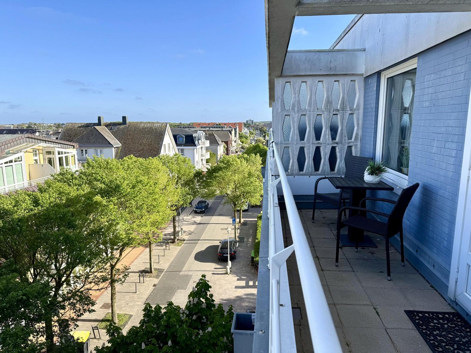 Balkon mit Tisch und Stühlen, Blick auf Straße und Häuser