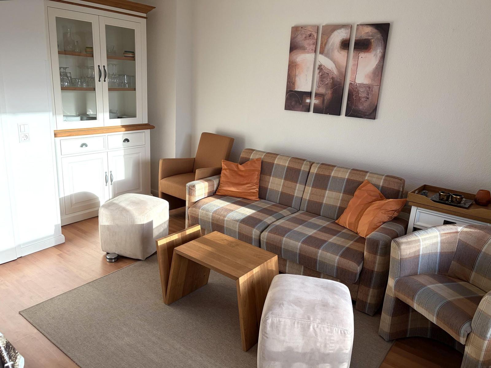 Wohnzimmer mit Sofa, Sessel und Tisch. An der Wand hängt ein Bild.