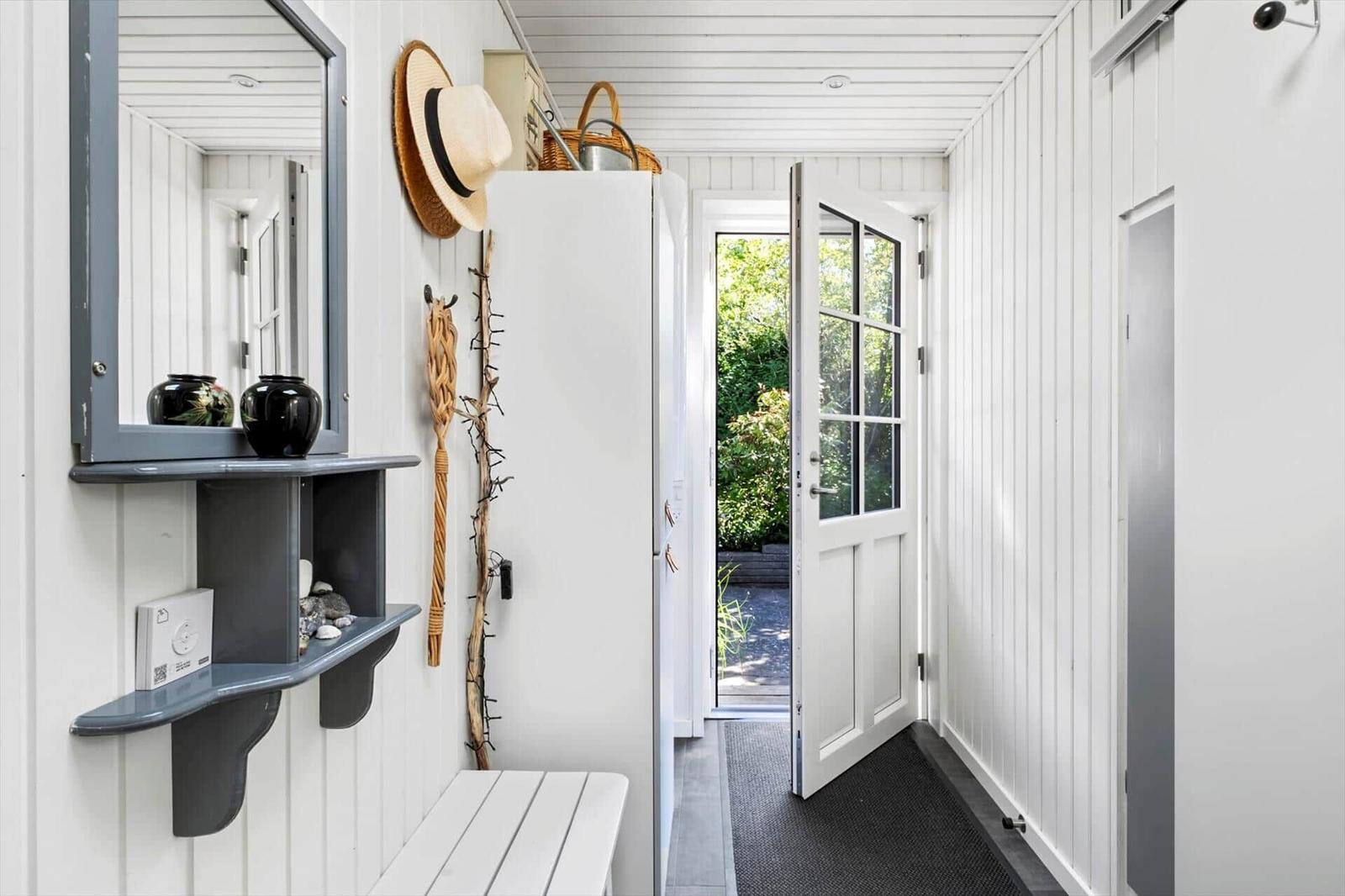 Entrance area with mirror cabinet, bench, and door to the garden.