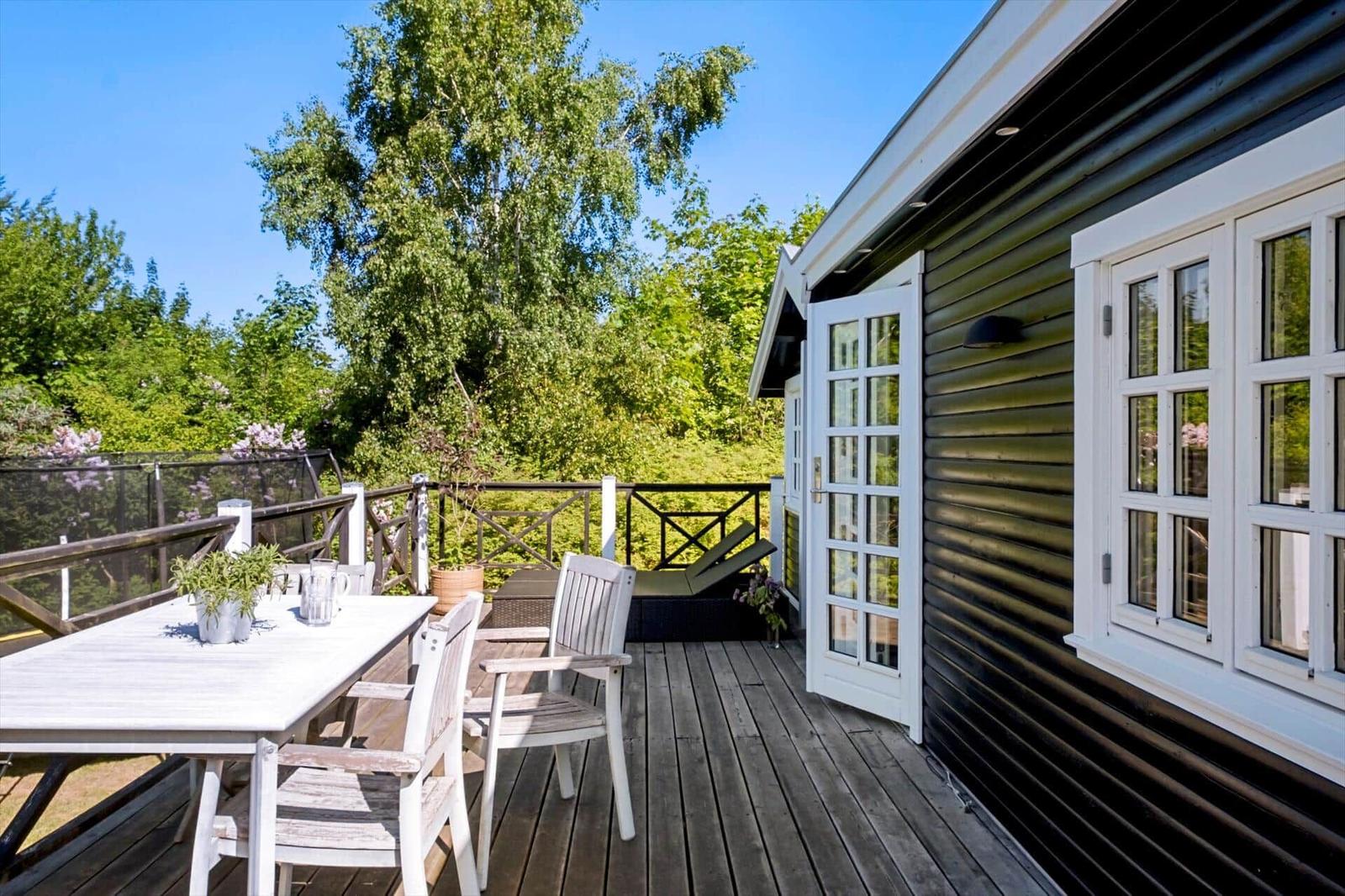 Deck with table, chairs, and view into green surroundings.