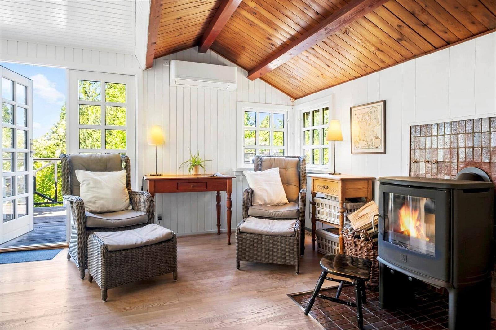 Living room with fireplace, two chairs, and view to balcony.
