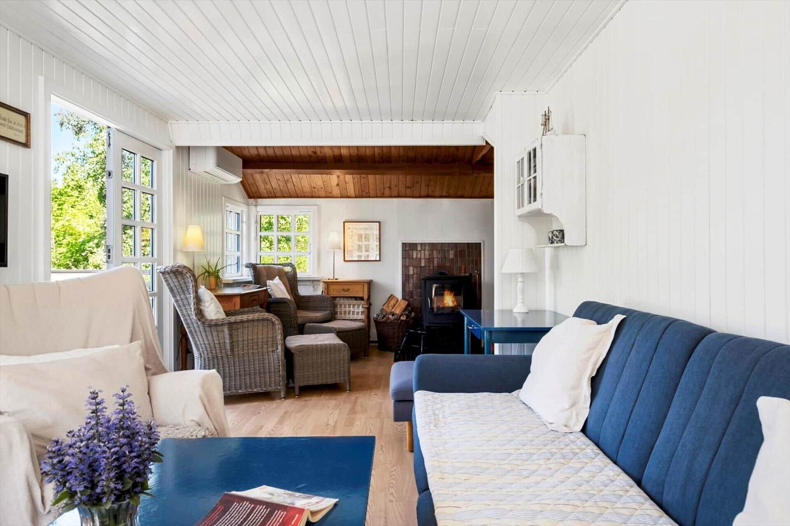 Living room with sofa, armchairs, and fireplace. Wooden floor and white walls.