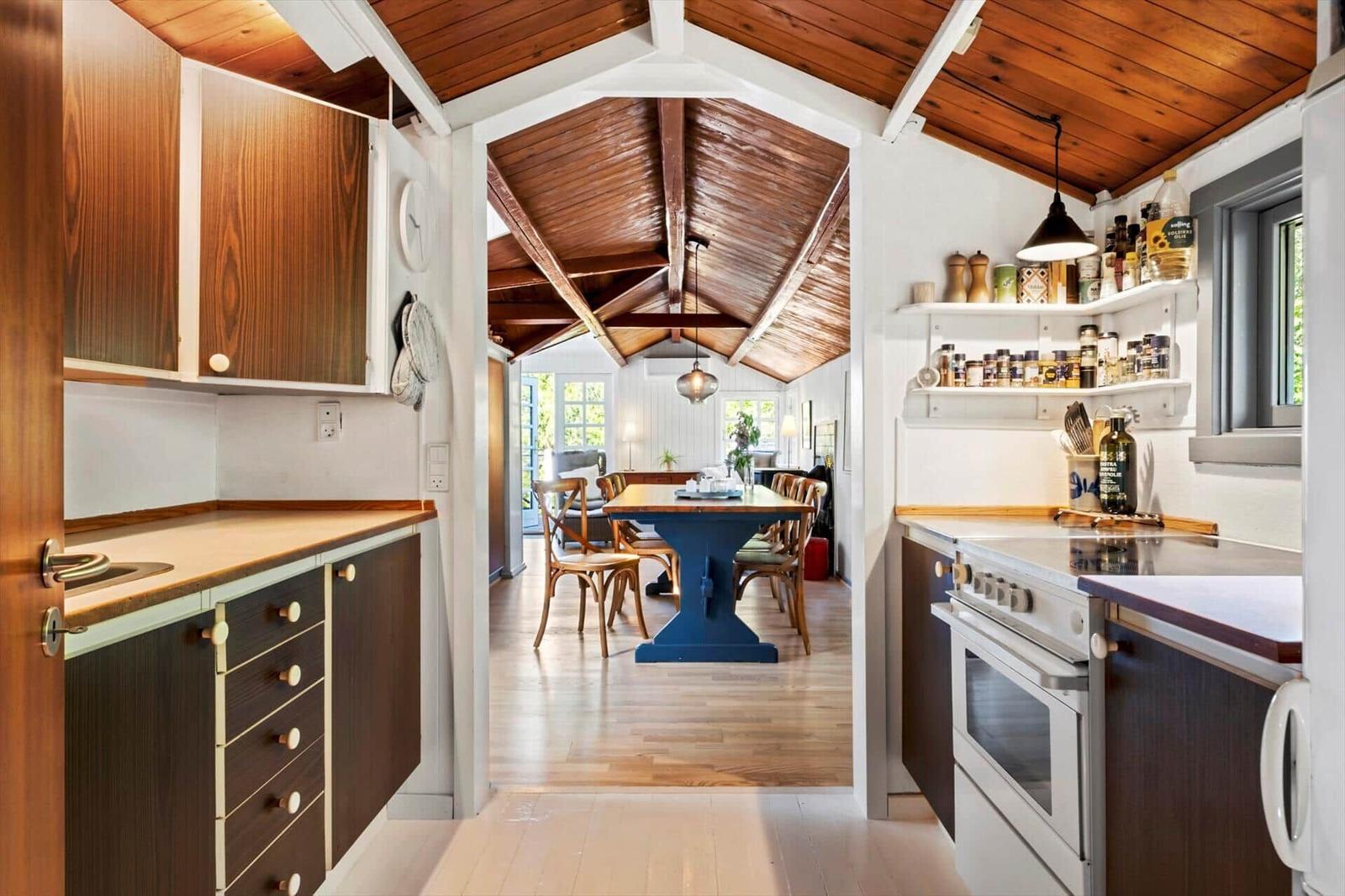 Kitchen with wooden surfaces and view into dining room with blue table.