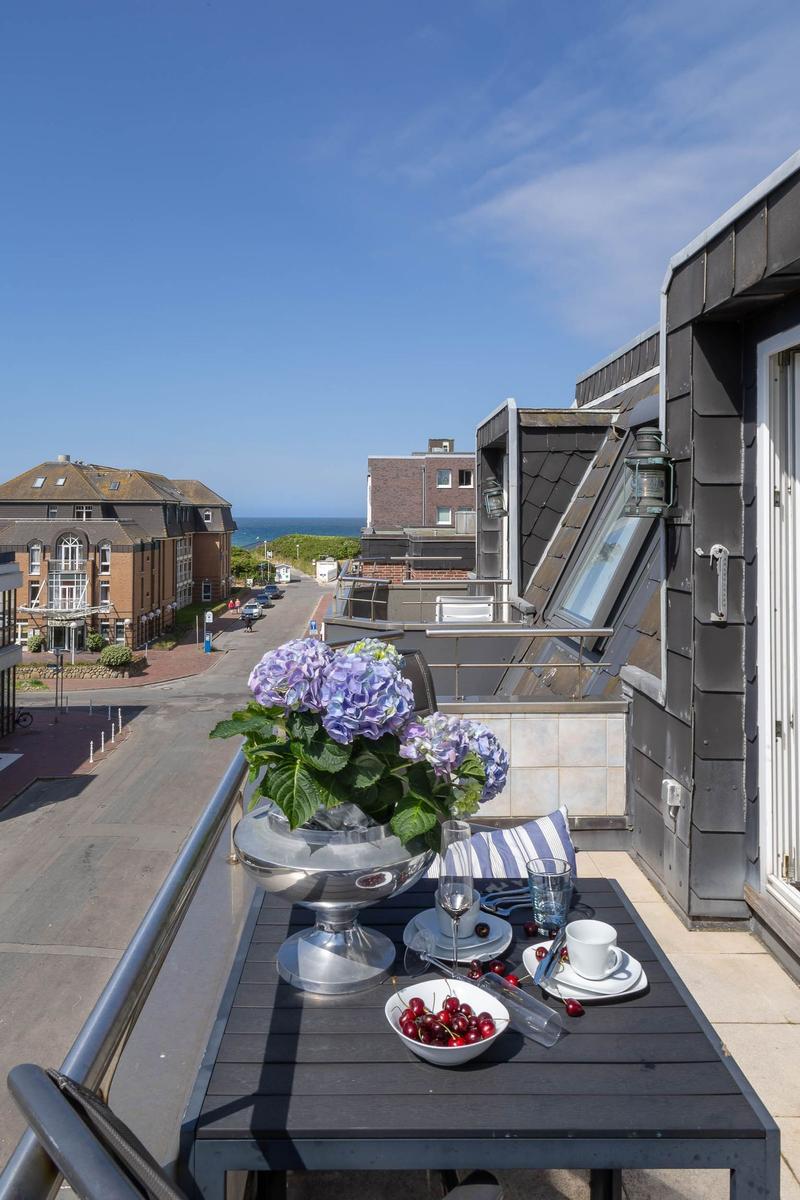 Balcony with table, flowers, and sea view.
