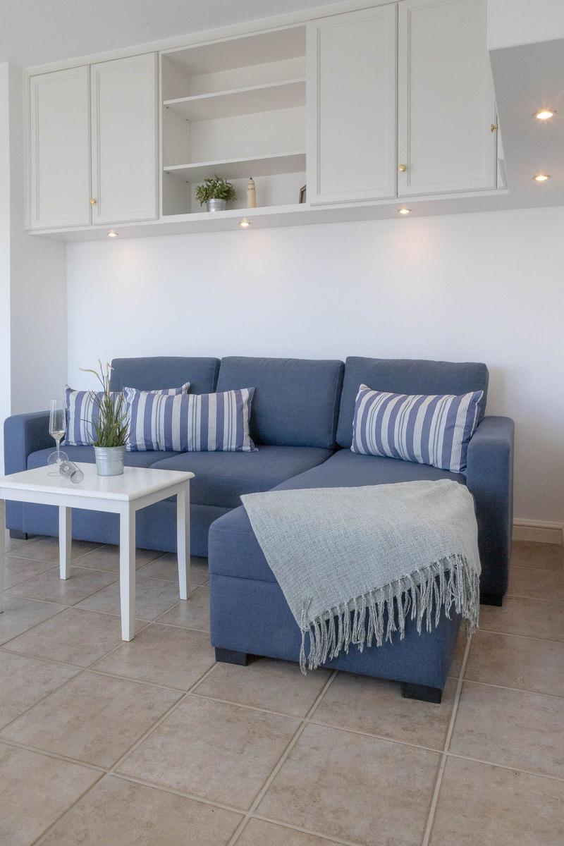 Ein Wohnzimmer mit blauem Sofa, weißen Schränken und einem kleinen Tisch.