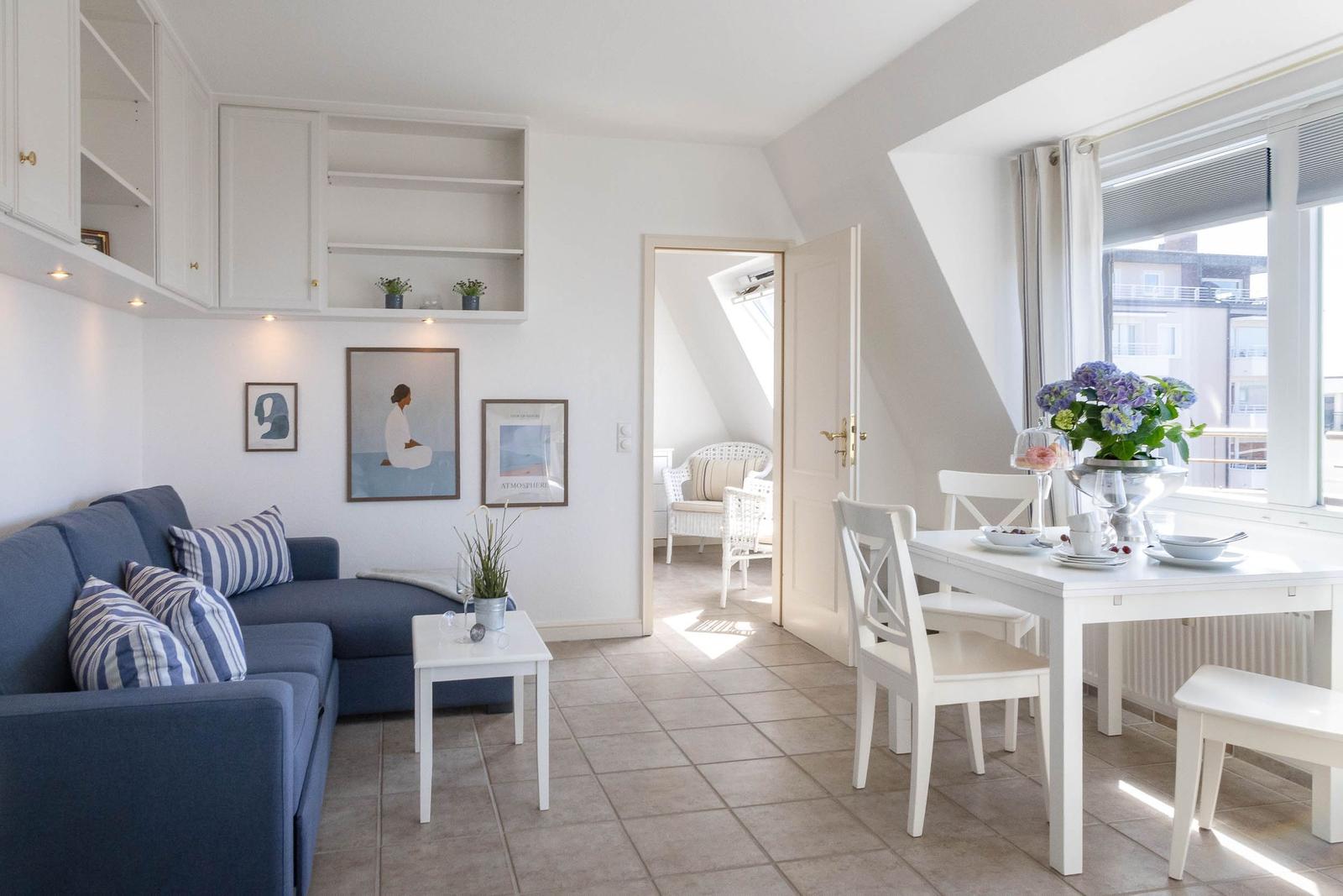 Wohn- und Essbereich mit Sofa, Esstisch und Blick auf Balkon.