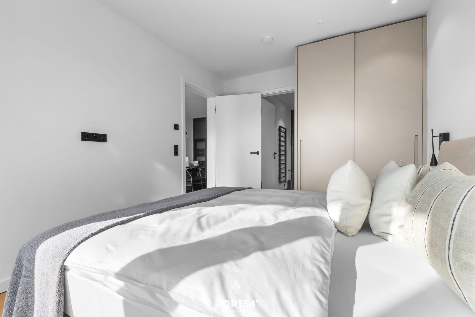 Schlafzimmer mit Bett, Kleiderschrank und Sicht in angrenzende Räume.