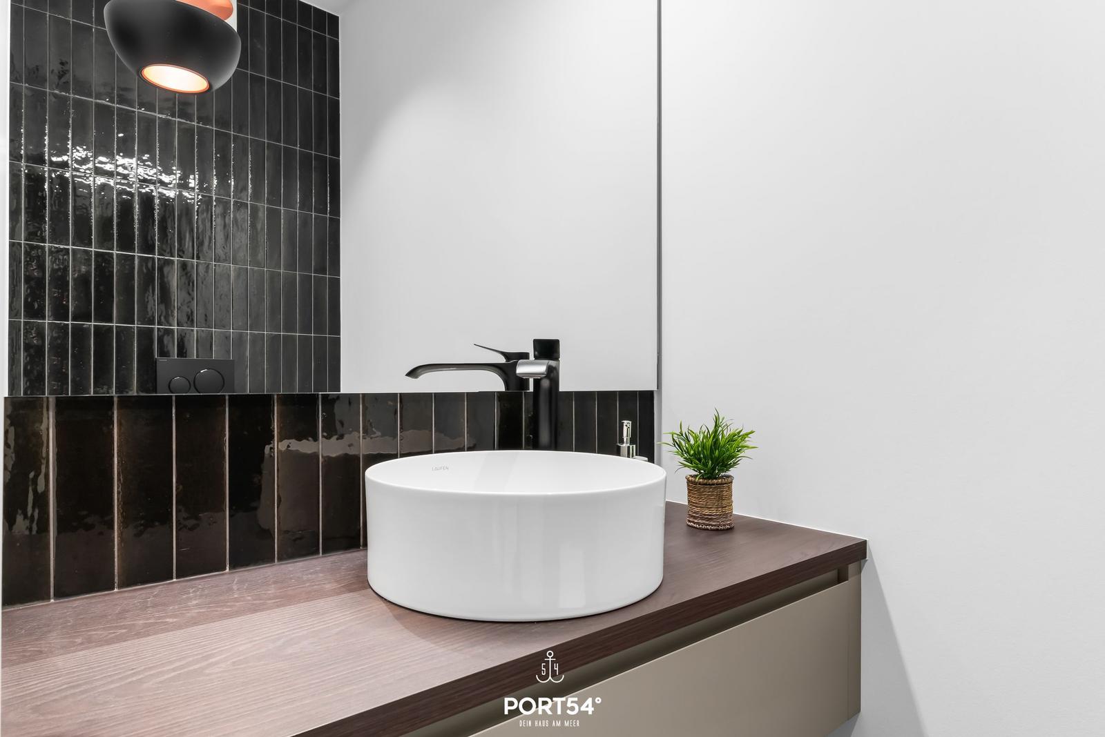 Waschbecken mit schwarzer Wand und Holzoberfläche