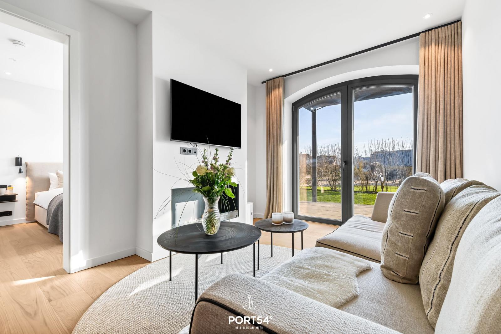 Wohnzimmer mit Sofa, TV und Blick auf die Terrasse.
