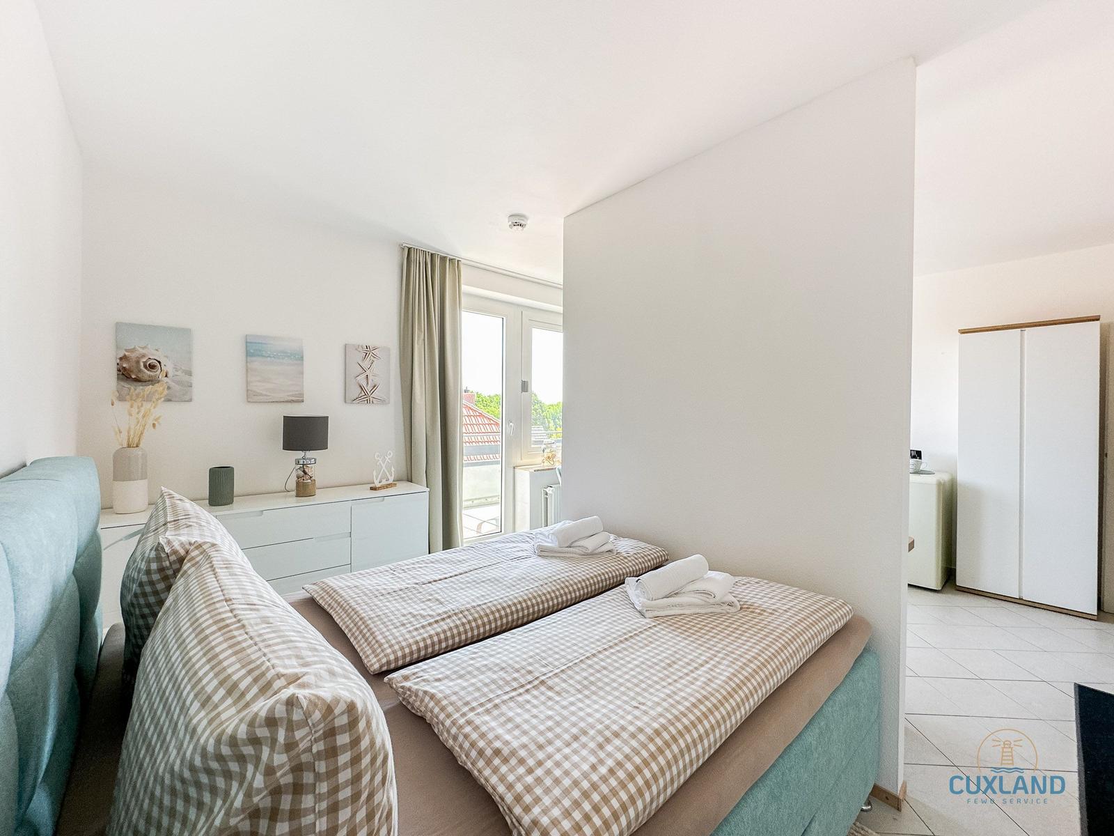 Zwei Schlafplätze mit Bettwäsche, Fenster mit Blick, Schrank und Wandbilder.