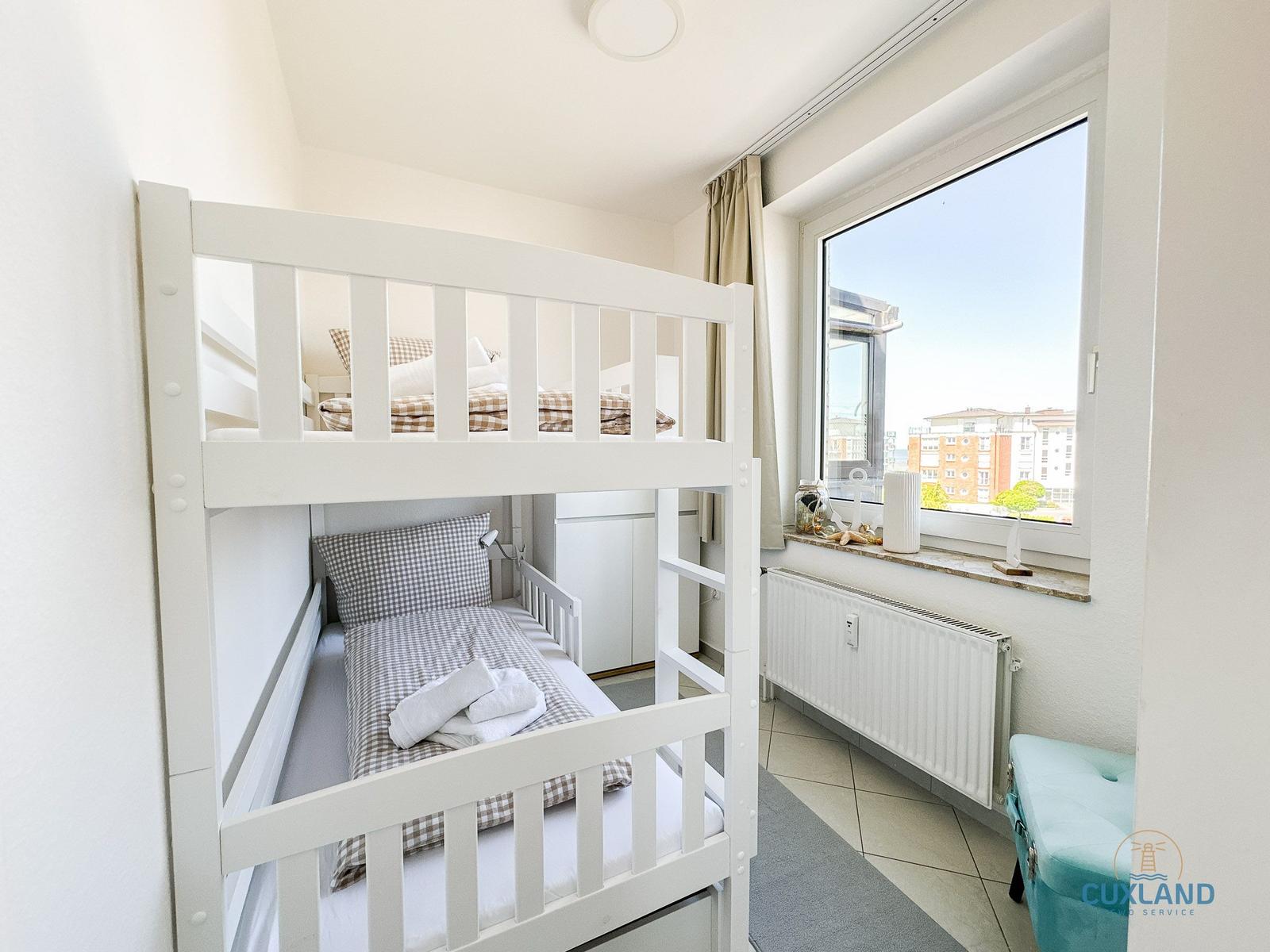 Zimmer mit Doppelstockbett, Fenster und Heizung.