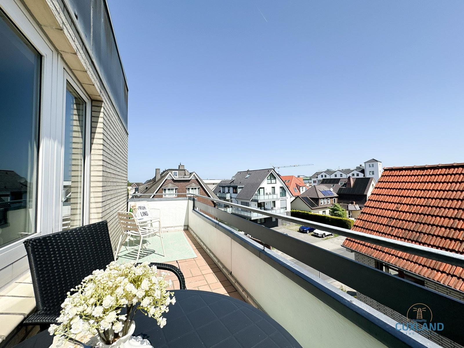 Terrasse mit Tisch, Stühlen und Blick auf Wohnhäuser und Dächer.