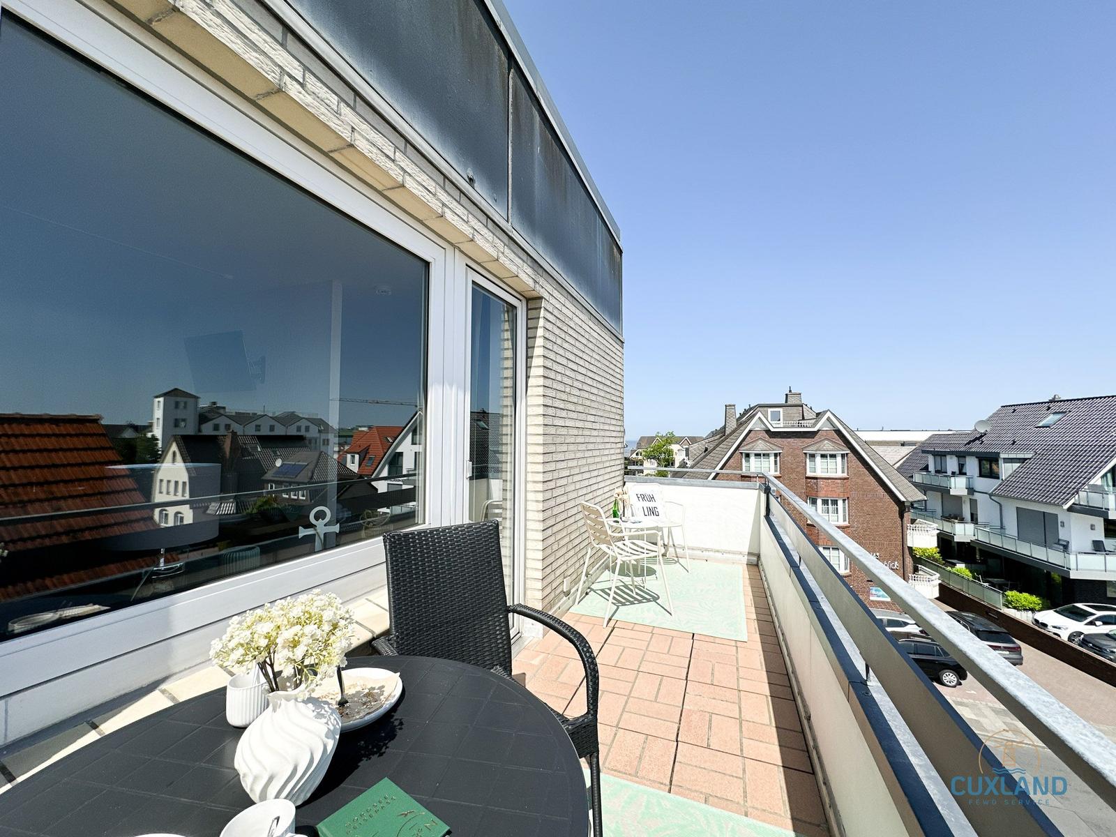 Terrasse mit Tisch, Stühlen und Blick auf Wohnhäuser.