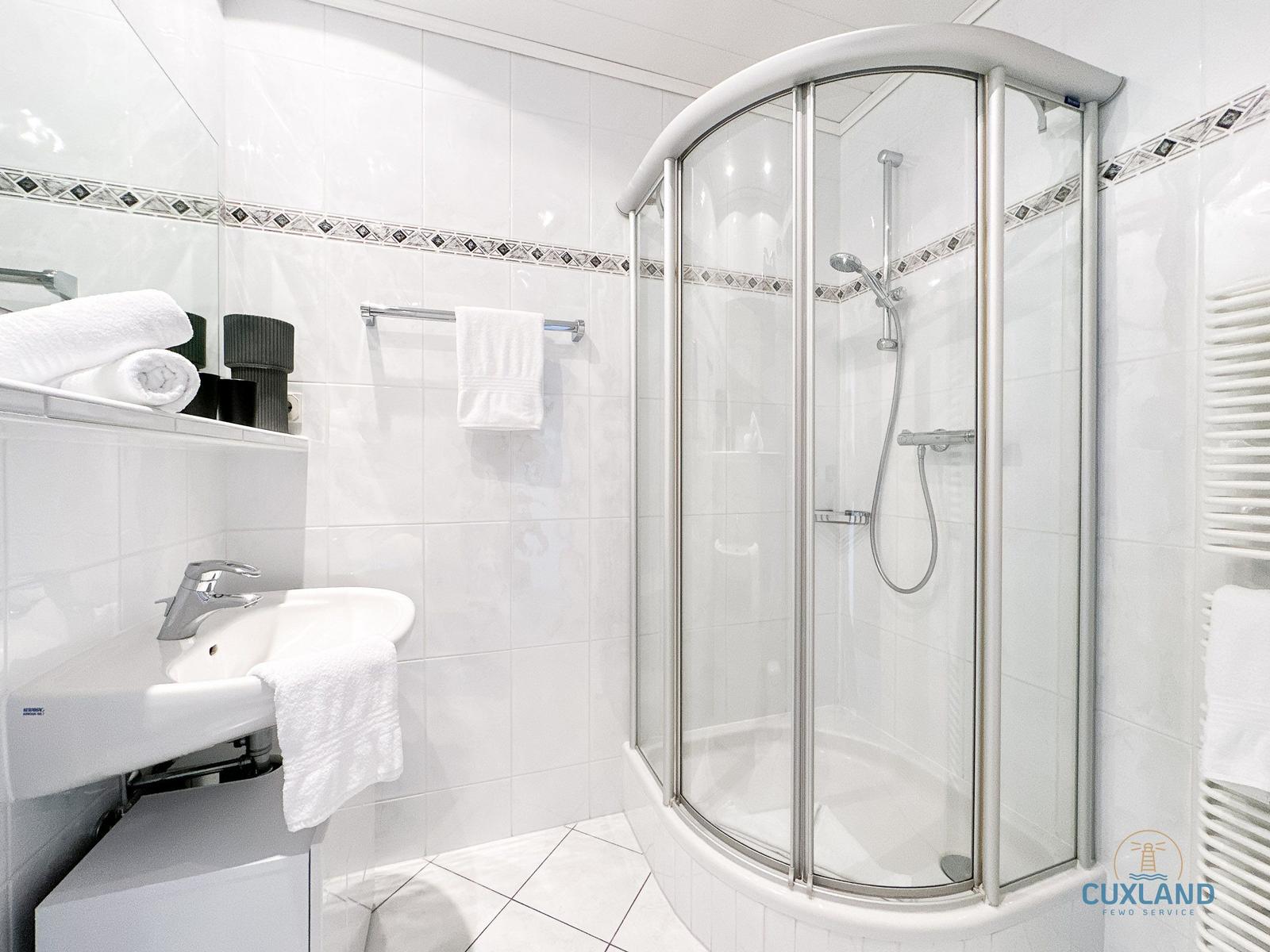 Badezimmer mit Dusche, Waschbecken und Handtüchern