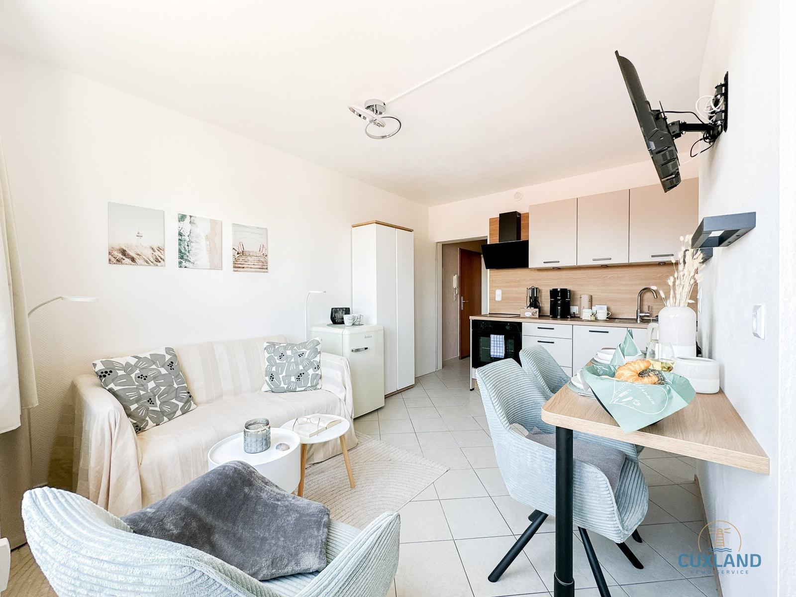 Wohnung mit Sofa, Esstisch, Küchenzeile und Wand-TV.