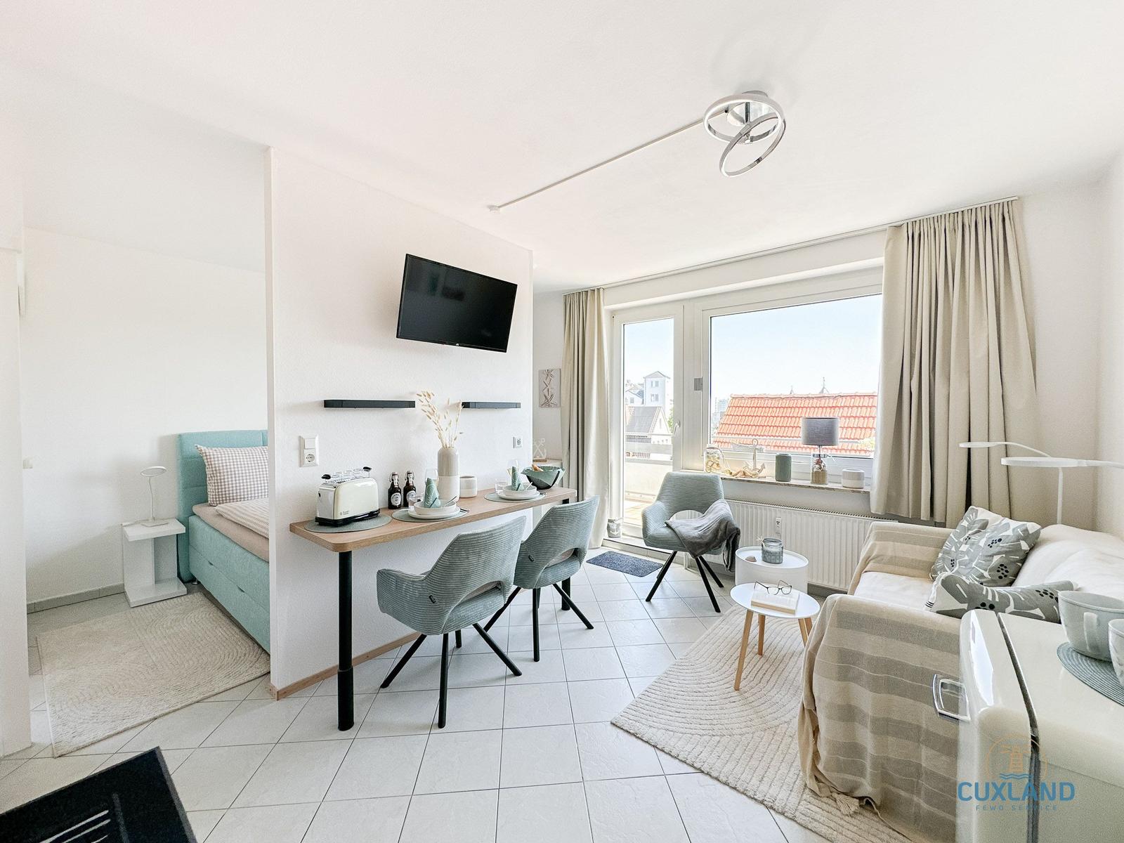 Wohnung mit Schlafplatz, Esstisch und Sofa. Fenster mit Blick auf Dachziegel.