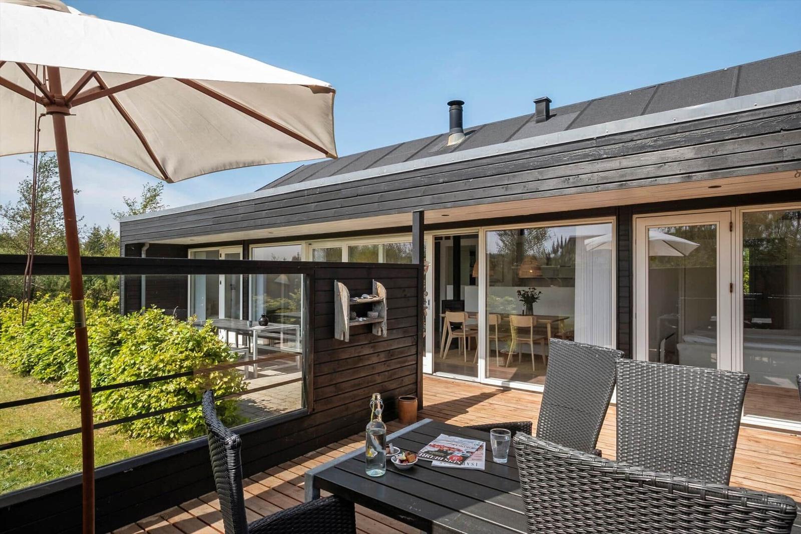 Terrace with table, chairs, and umbrella. Glass doors lead to the interior.