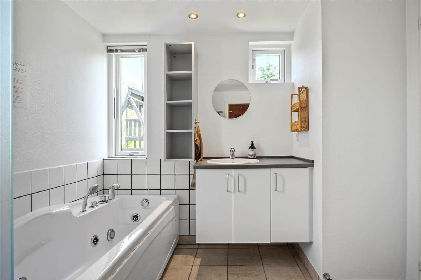 Bathroom with bathtub, sink, and windows.