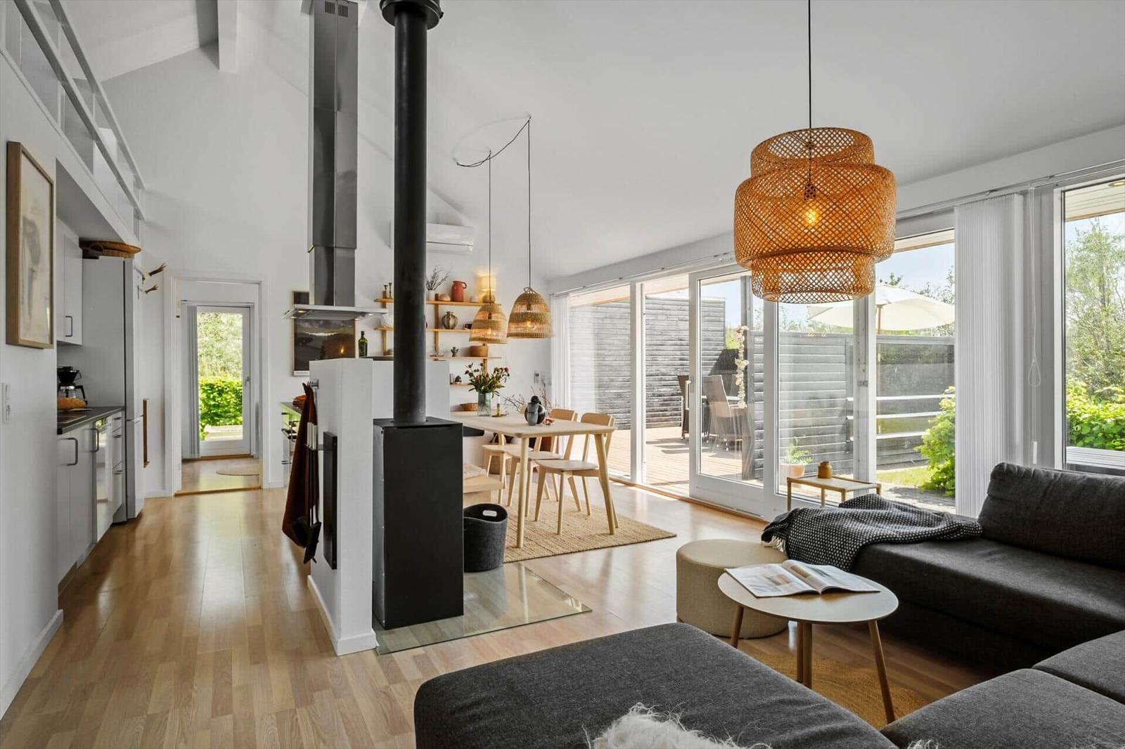 Living and dining area with fireplace, wooden floor, and large window to the garden.