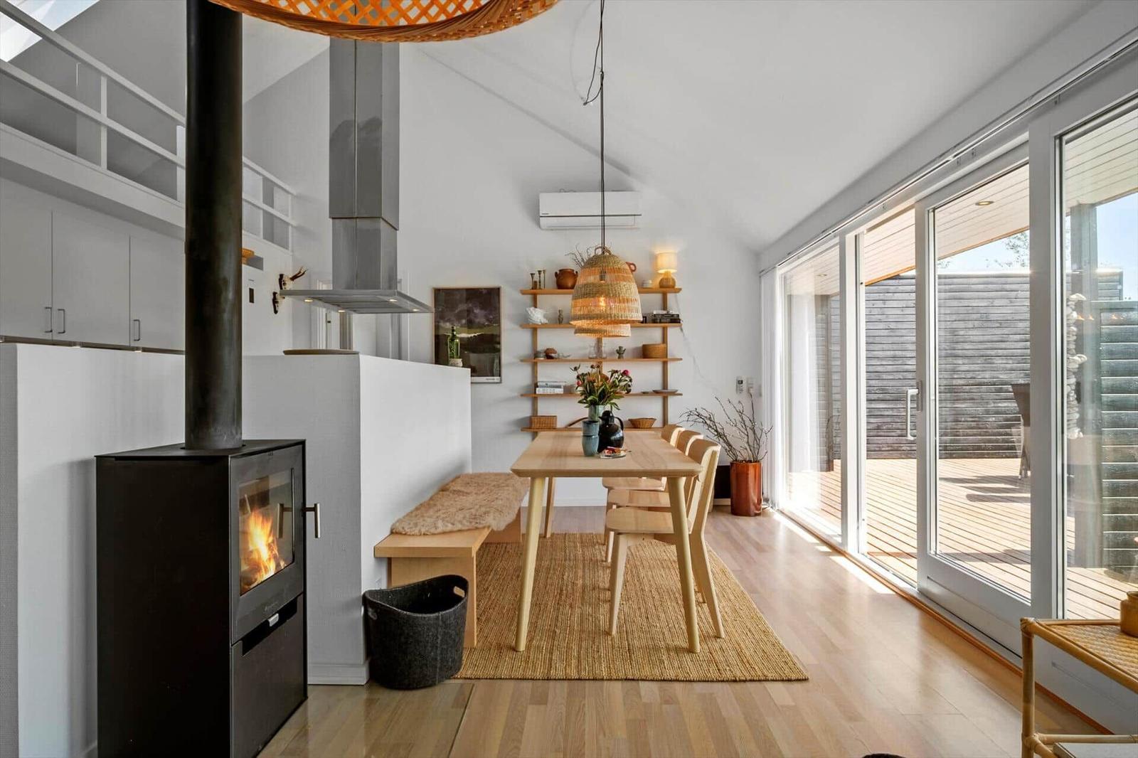 Dining area with wooden table, chairs, and view of the terrace.