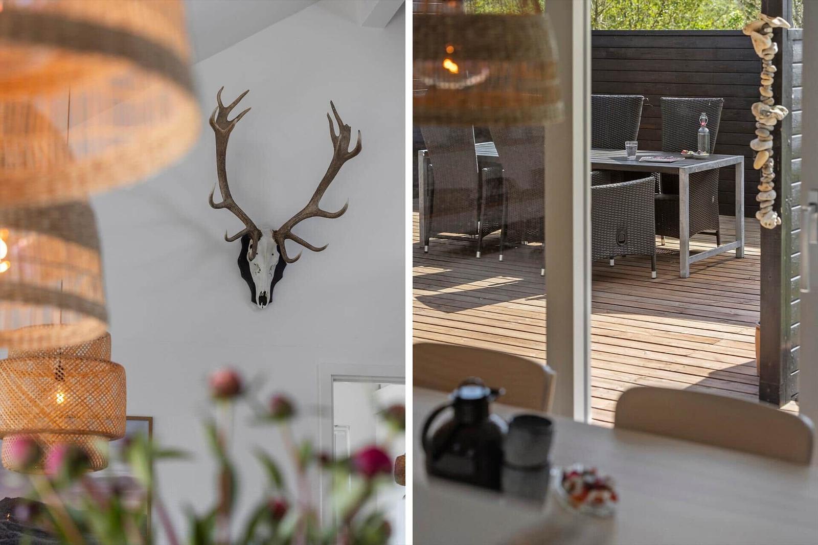 Living area with deer antlers on the wall and view of the terrace with table and chairs.