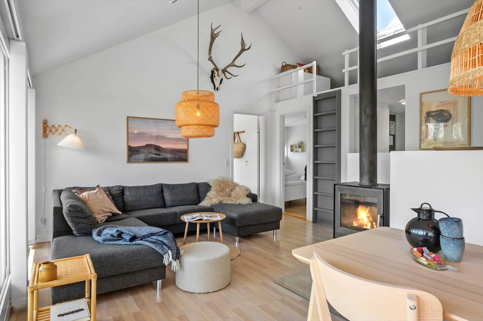 Living area with sofa, fireplace, and dining space. Wooden floor and light walls.