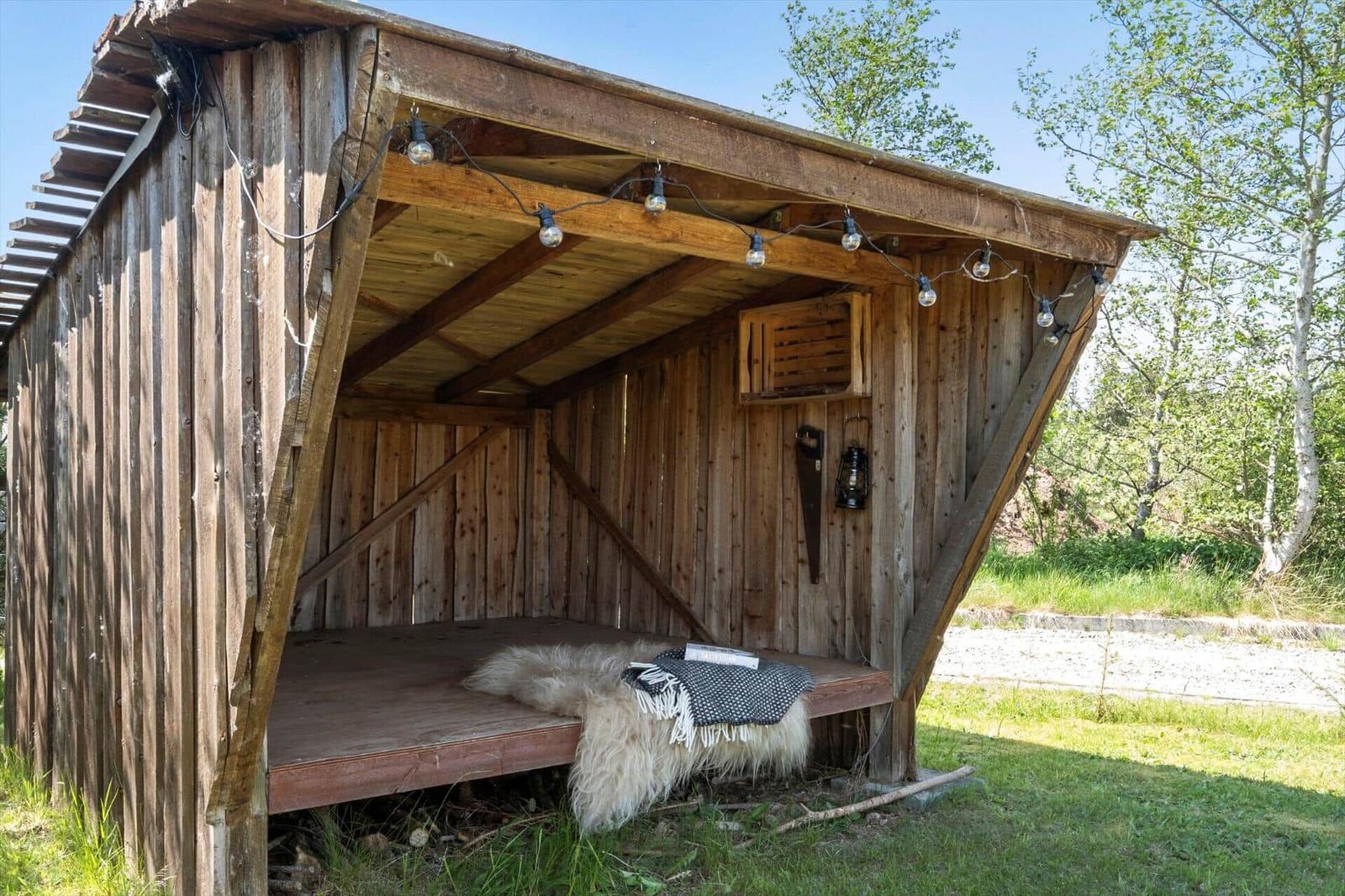 Wooden structure with roof, seating area, ceiling lights, and wall mounts.