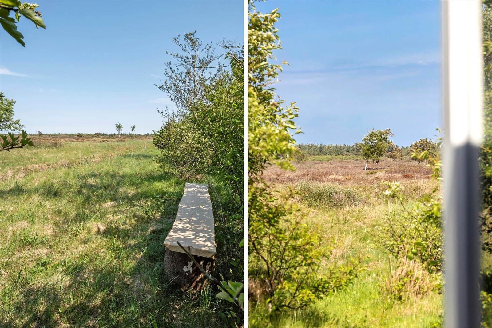 A long stone bench outdoors with a view of a green meadow and trees.
