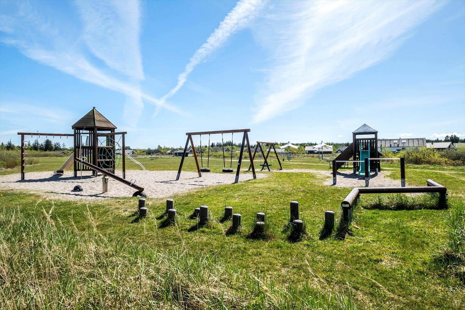 Large playground with climbing frame, swings, and slide on green grass.