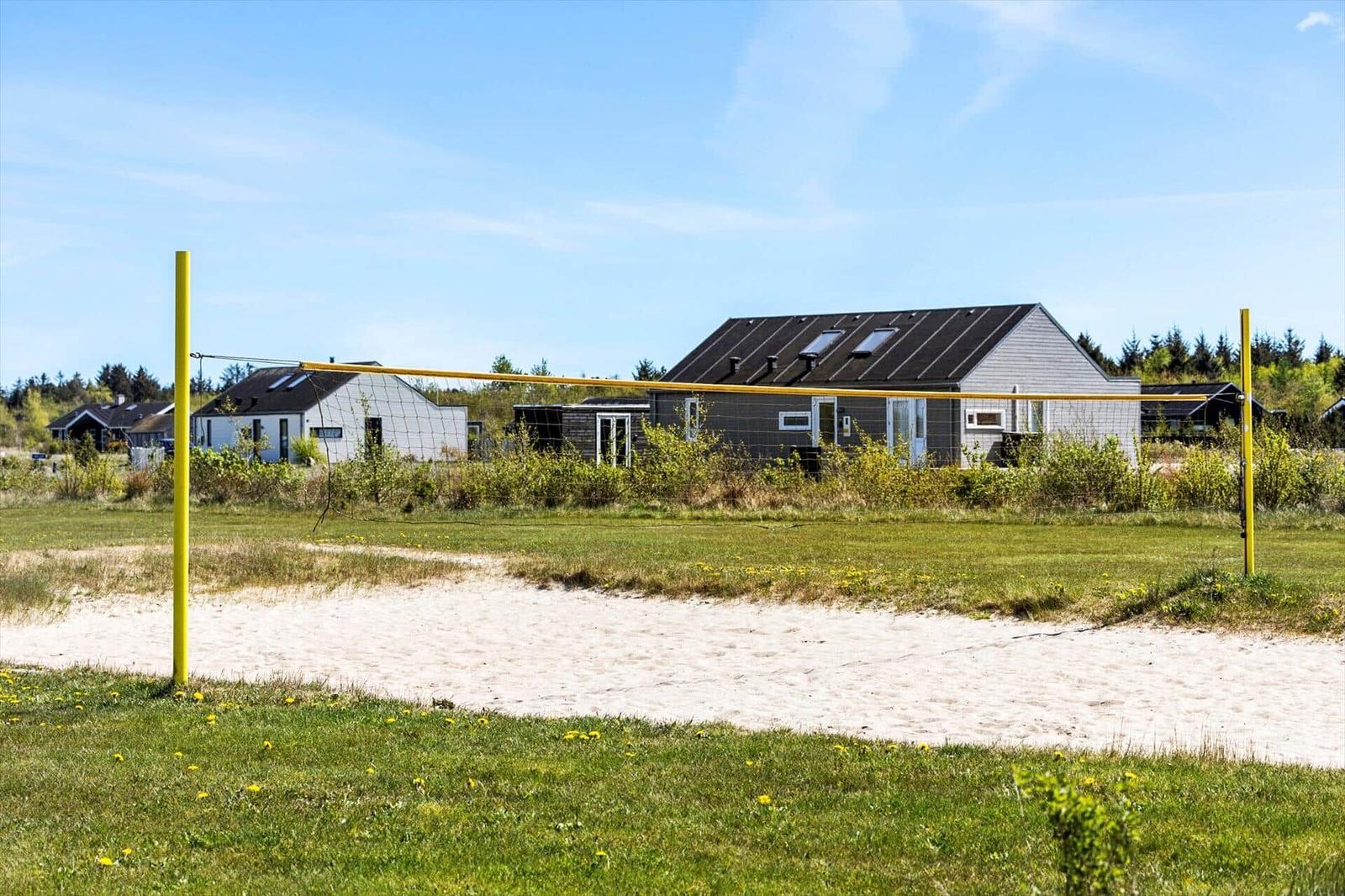 Volleyball net in front of beach house with grass and sand
