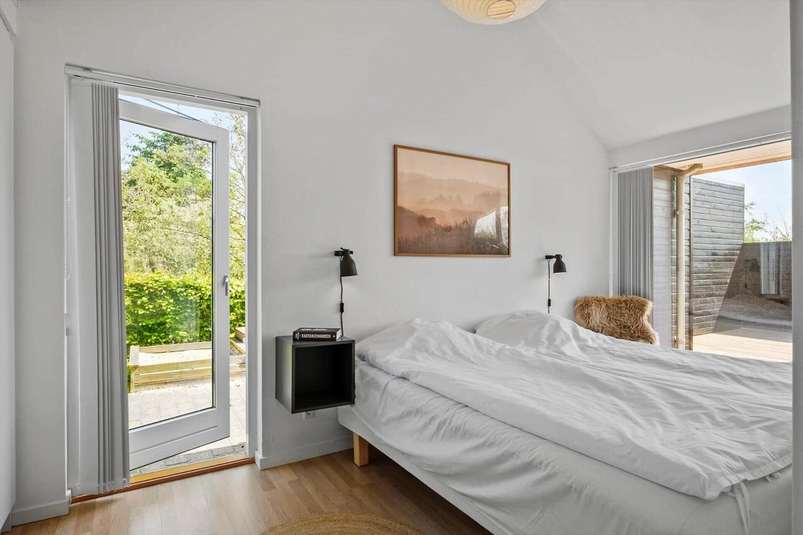 Bedroom with bed, wall art, and doors to outdoor area.
