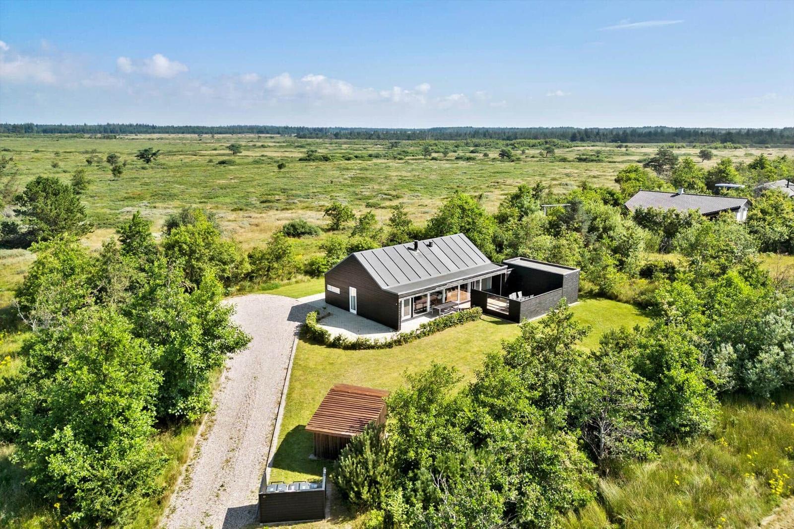 Modern wooden cabin with terrace and garden in rural surroundings.