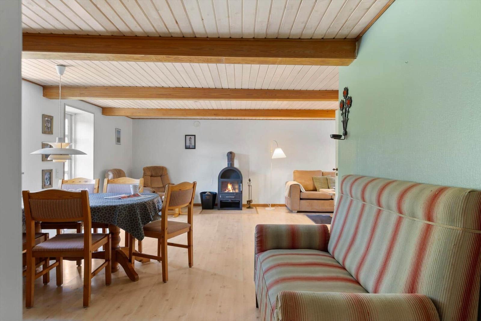 Living and dining area with fireplace, sofa, and wooden table.