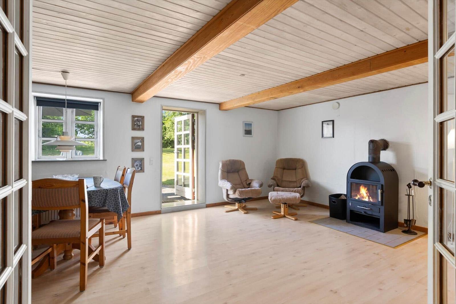 Room with wooden floor, fireplace, and recliners. Windows and door lead outside.