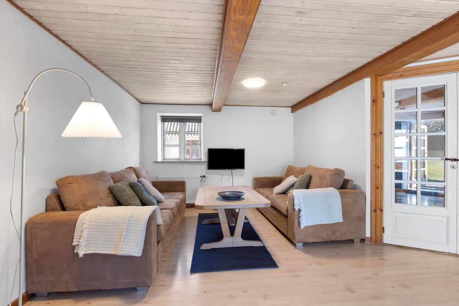 Living room with two sofas, table, TV, and door to outdoor area.