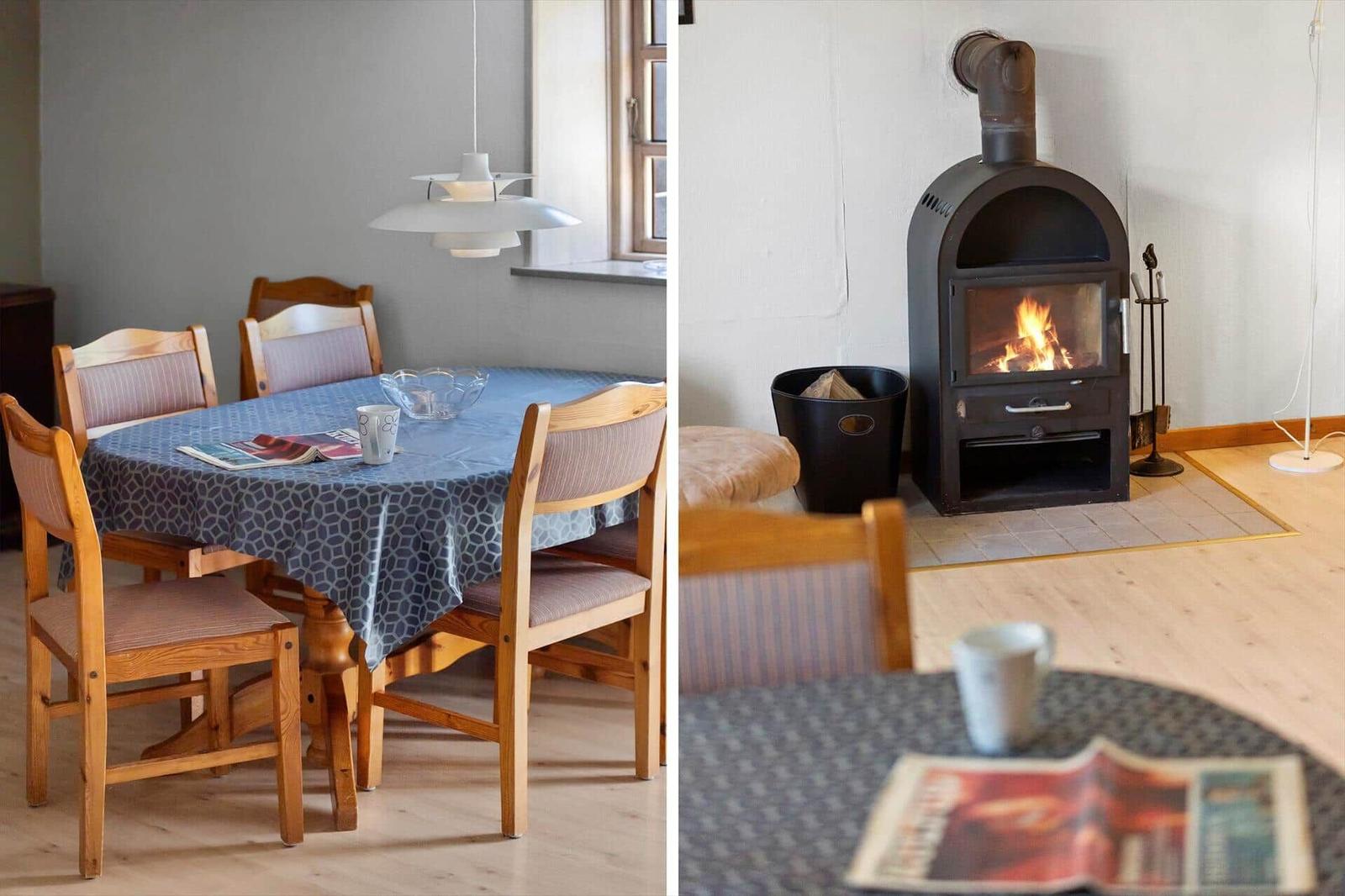 Dining room with wooden table and chairs. Fireplace with burning wood.