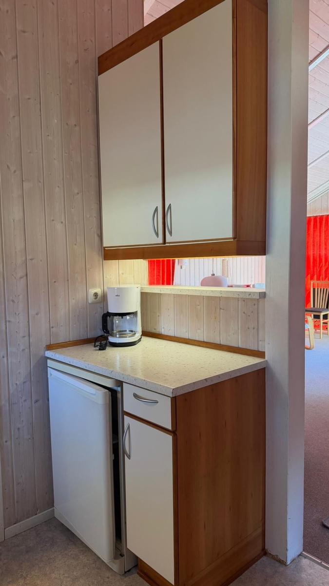 Küchenbereich mit Kühlschrank, Kaffeemaschine und Holzschränken.