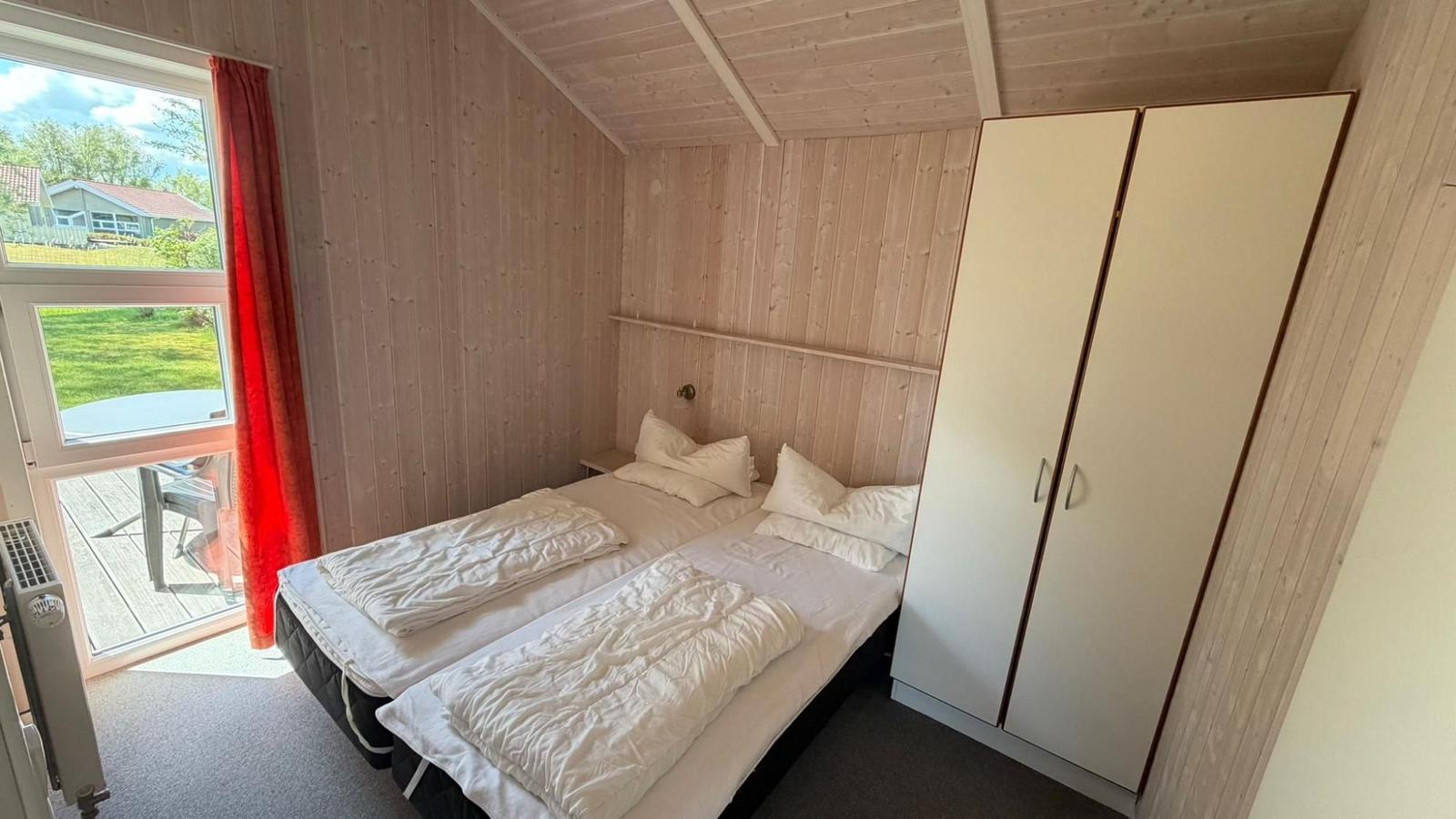 Zwei Einzelbetten, Kleiderschrank und Fenster mit Blick auf die Terrasse.