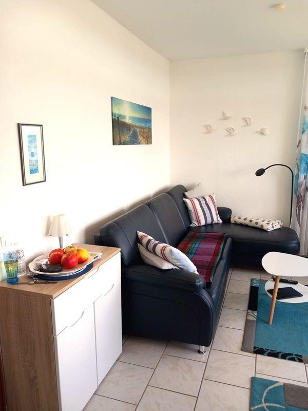 Wohnzimmer mit Sofa, Tisch und Wandbildern.
